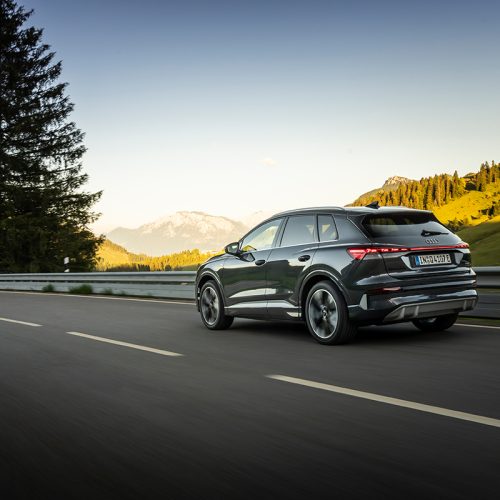 Audi Q4 SUV e-tron in Tamboragrey, outdoor driving shot, exterior, rear three-quarter view in an alpine landscape.